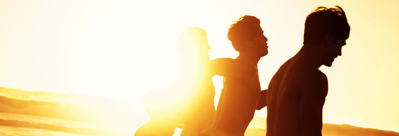 Men running on the beach, sunlight on the beach, surfers