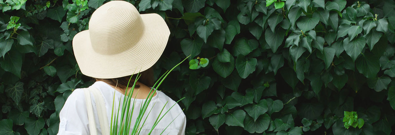 Woman in white hat, eco-friendly fashion, eco-conscious fashion, woman looking at green wall